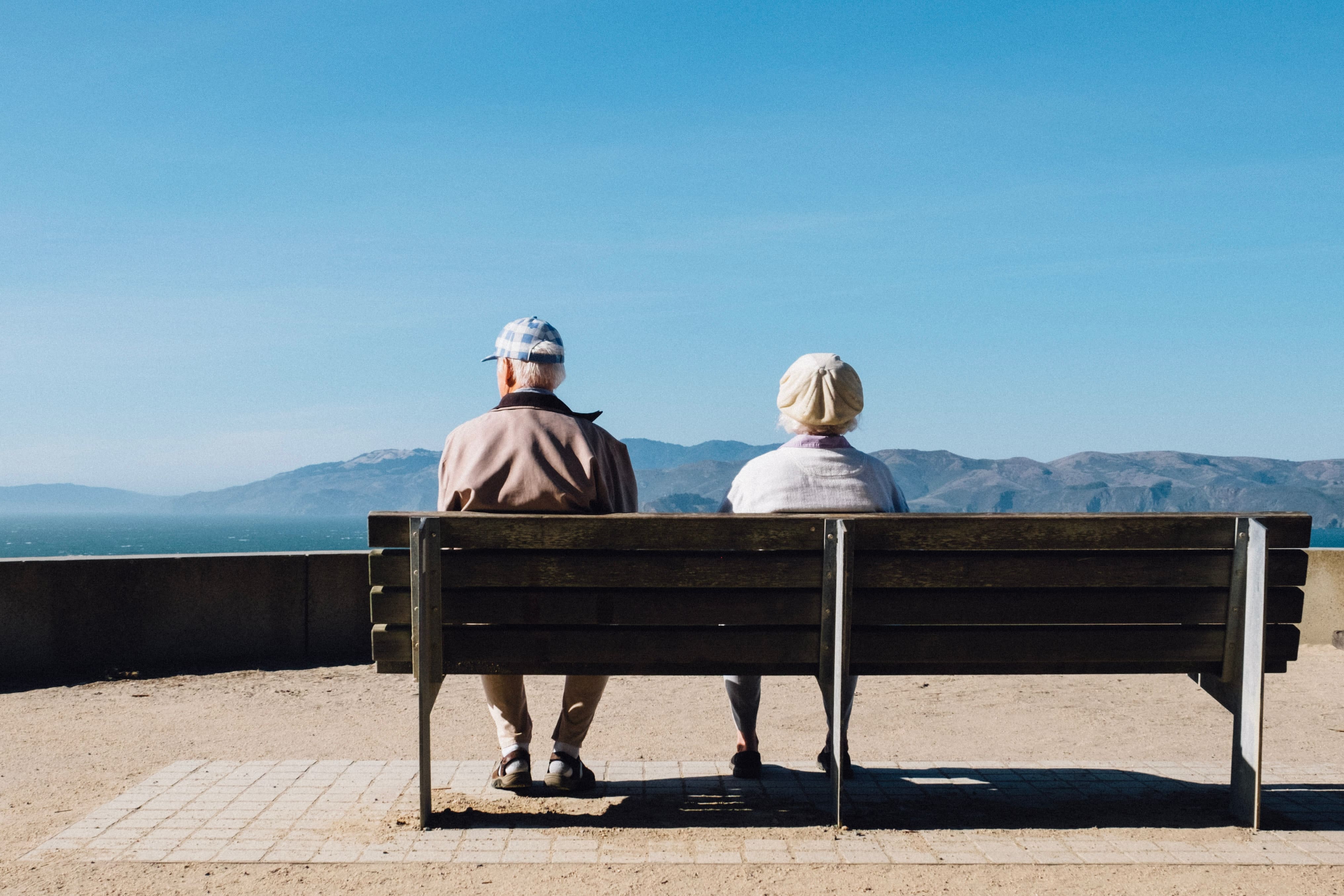 two older people on a bench representing the idea of spousal support into retirement age