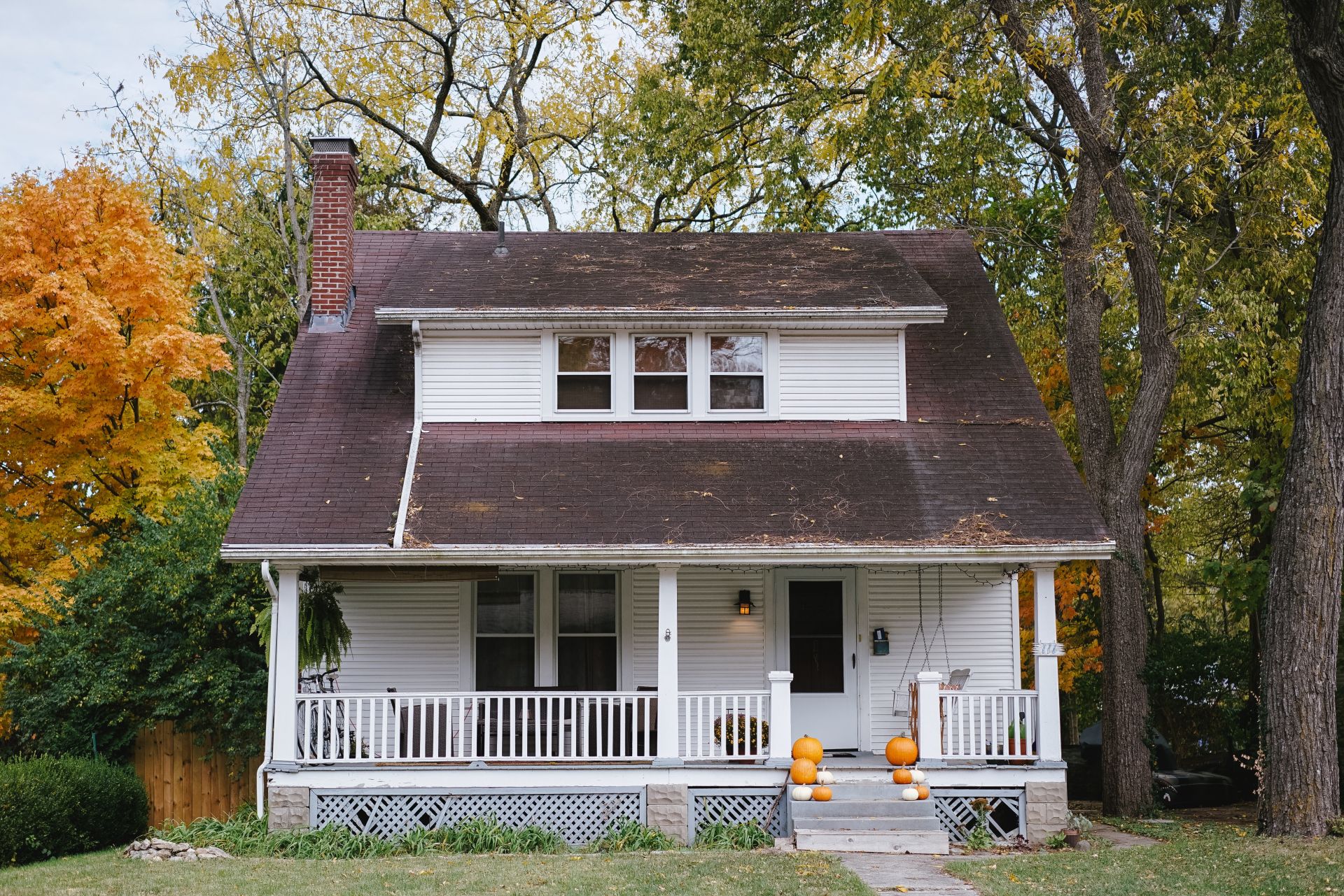 A white house with a porch and trees in the background