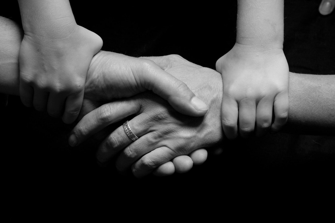 Adults shaking hands connected by a child's hands, representing parents working together to share access during the pandemic