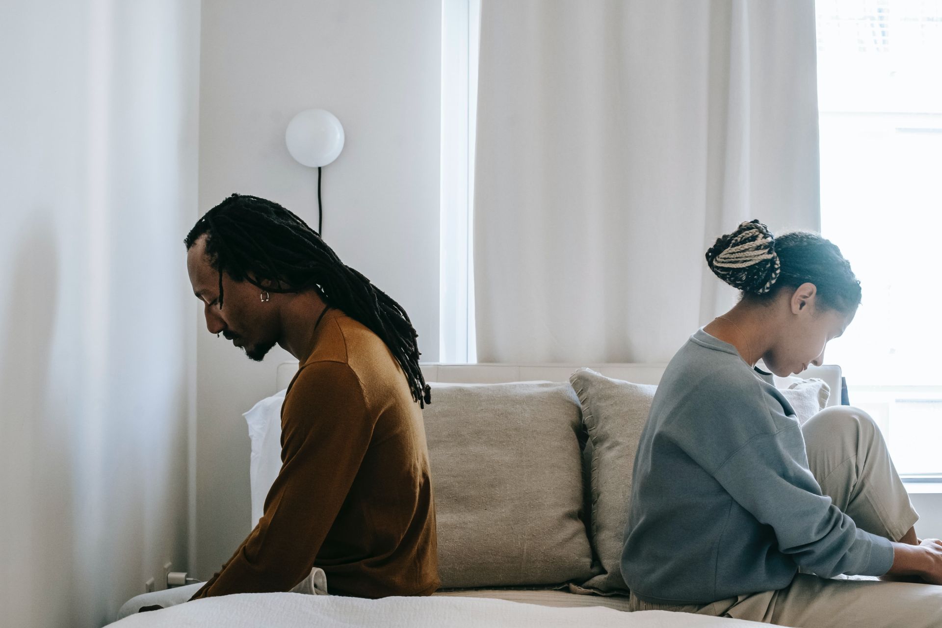 concerned black couple sits on bed