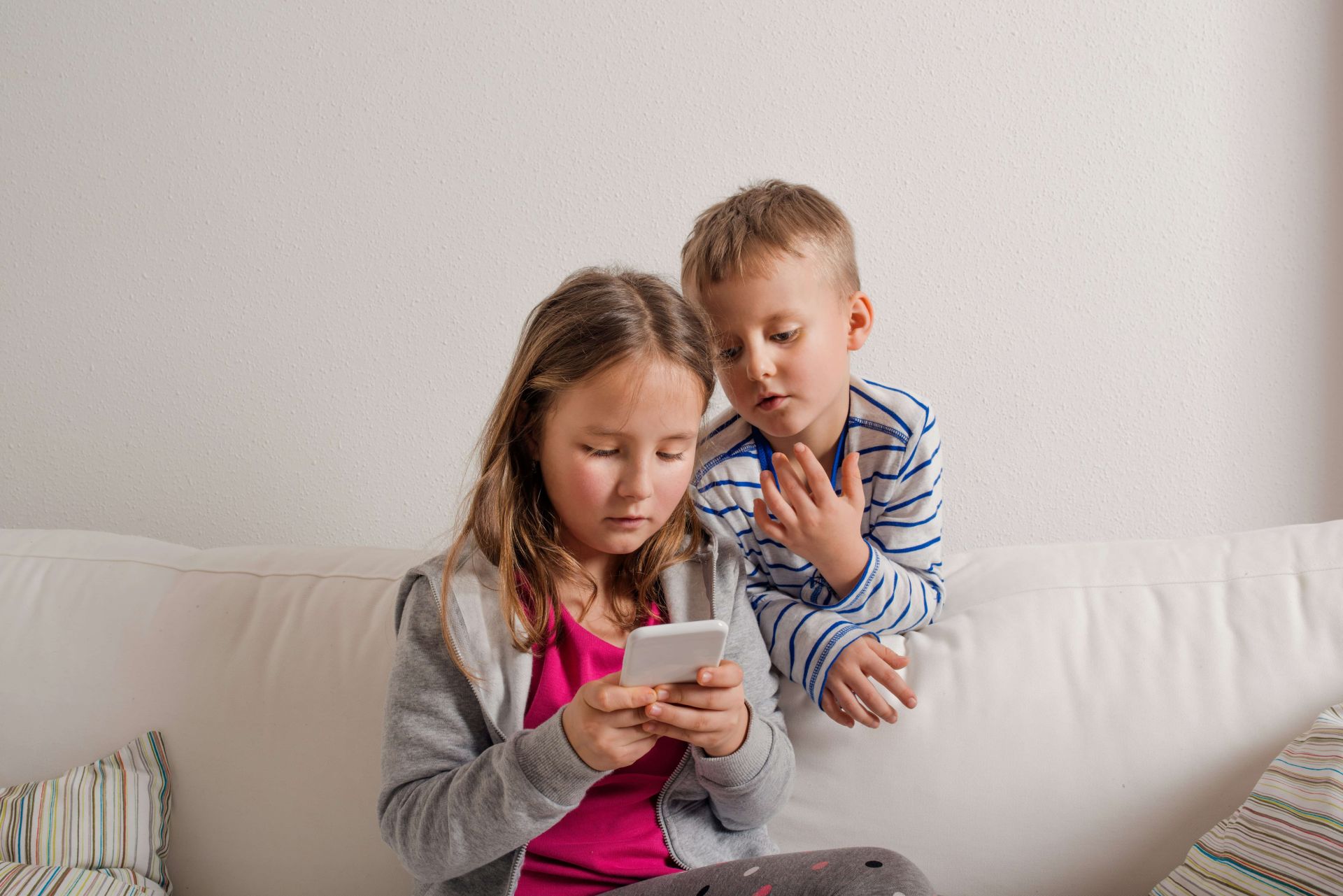 A young boy and a girl looking at a cell phone, representing co-parenting apps in Alberta
